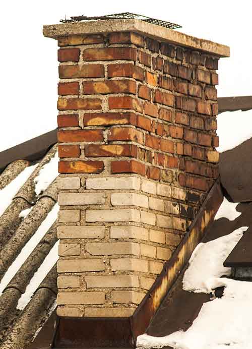 Brick Chimney with older bricks on roof with melted snow