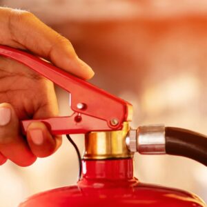 a hand about to squeeze the handle of a fire extinguisher