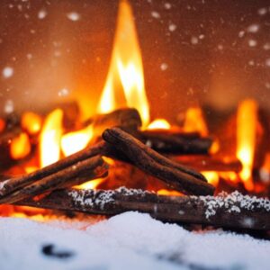 fire and logs blazing amongst snow falling