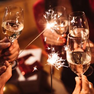 people clinking wine glasses with sparklers amongst them